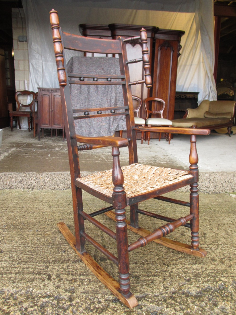 A 19th-century dark beech rocking armchair featuring turned spindle details and a hand-woven seagrass seat. View II