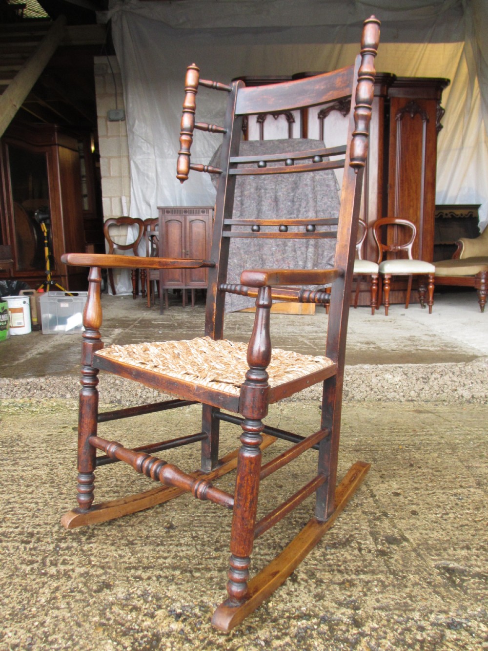 A 19th-century dark beech rocking armchair featuring turned spindle details and a hand-woven seagrass seat. View III