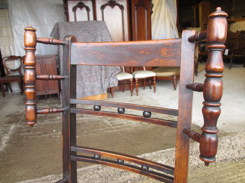 A 19th-century dark beech rocking armchair featuring turned spindle details and a hand-woven seagrass seat. View IV