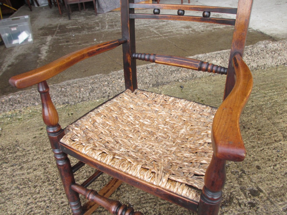 A 19th-century dark beech rocking armchair featuring turned spindle details and a hand-woven seagrass seat. View V