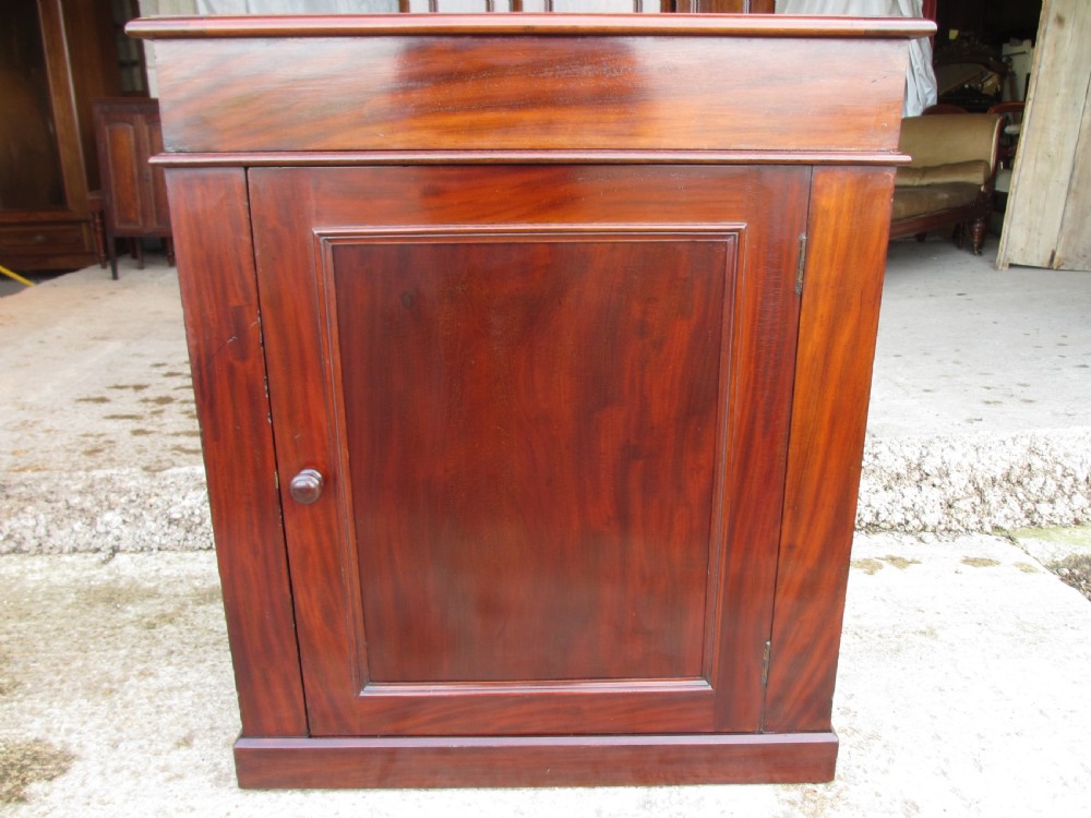 A Victorian flame mahogany washstand cupboard with a single panelled door, wooden knob handle, and plinth base.