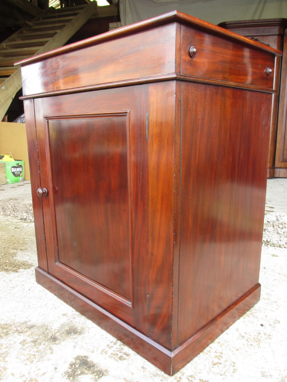 A Victorian flame mahogany washstand cupboard with a single panelled door, wooden knob handle, and plinth base. View II