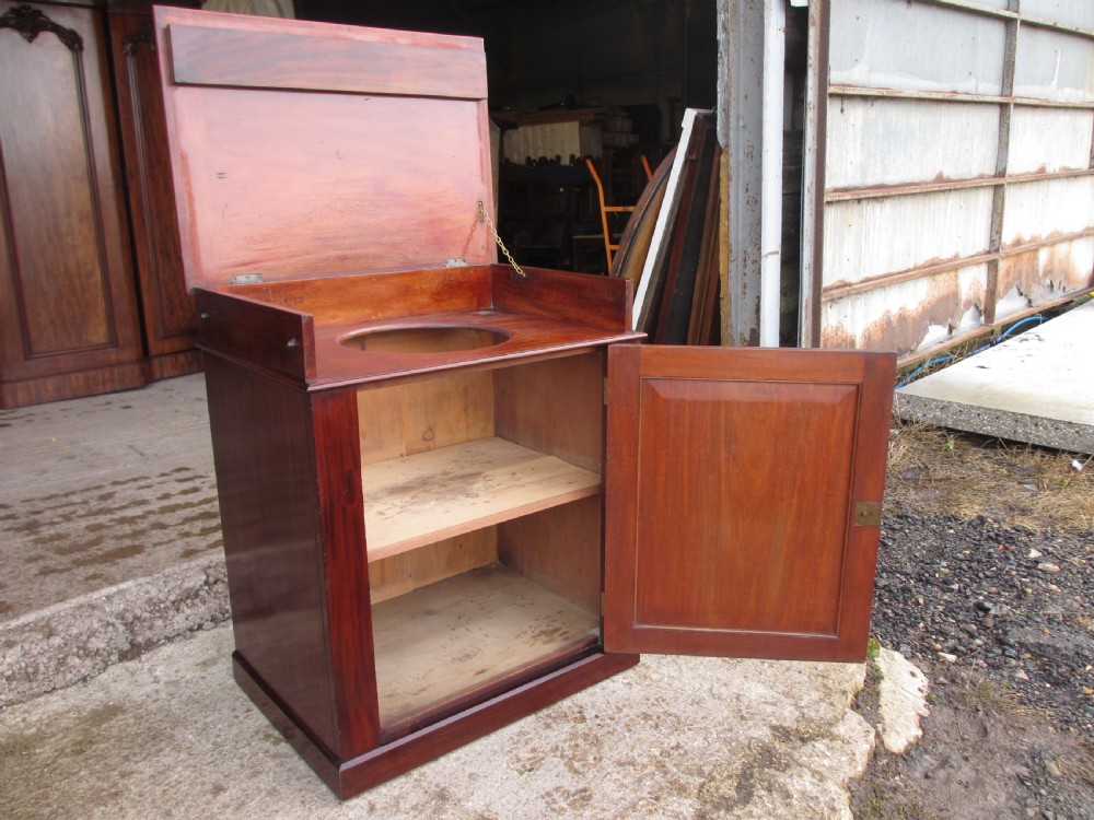 A Victorian flame mahogany washstand cupboard with a single panelled door, wooden knob handle, and plinth base. View IV