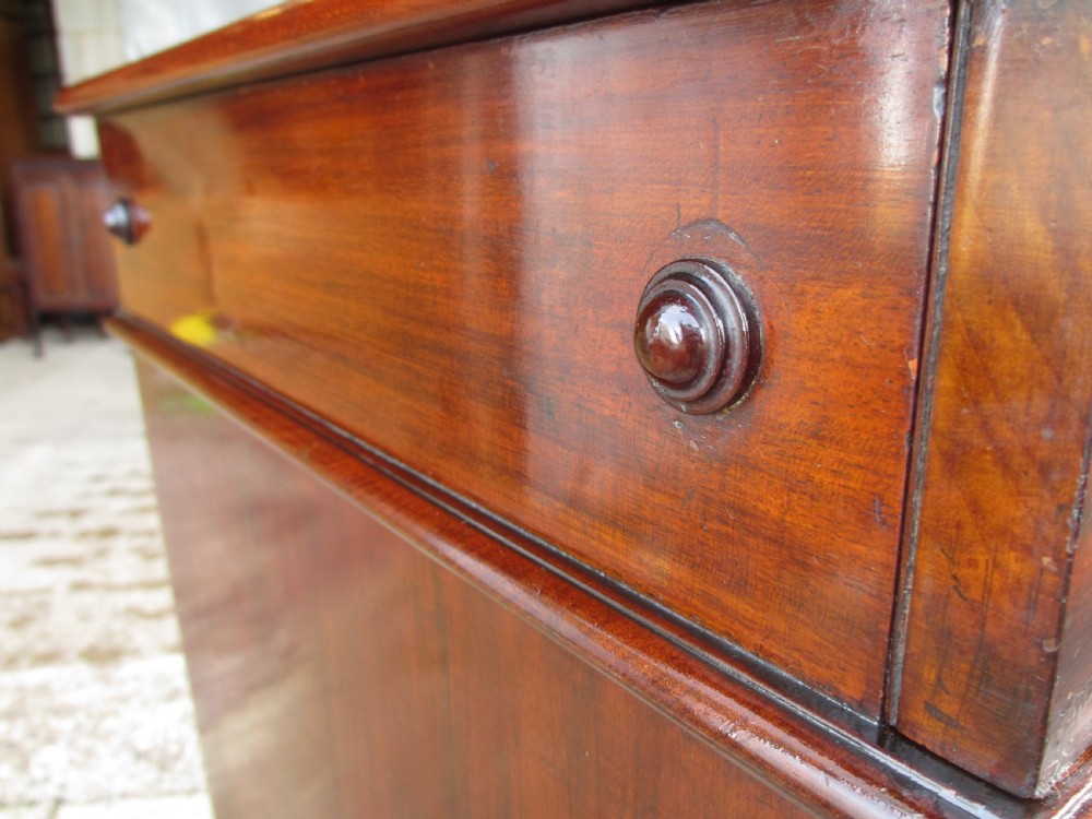 A Victorian flame mahogany washstand cupboard with a single panelled door, wooden knob handle, and plinth base. View VI