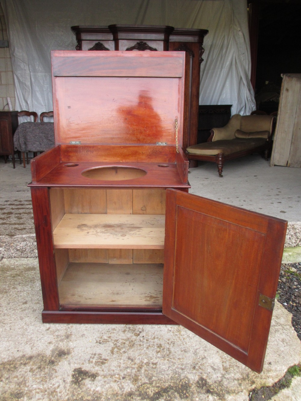 A Victorian flame mahogany washstand cupboard with a single panelled door, wooden knob handle, and plinth base. View VII