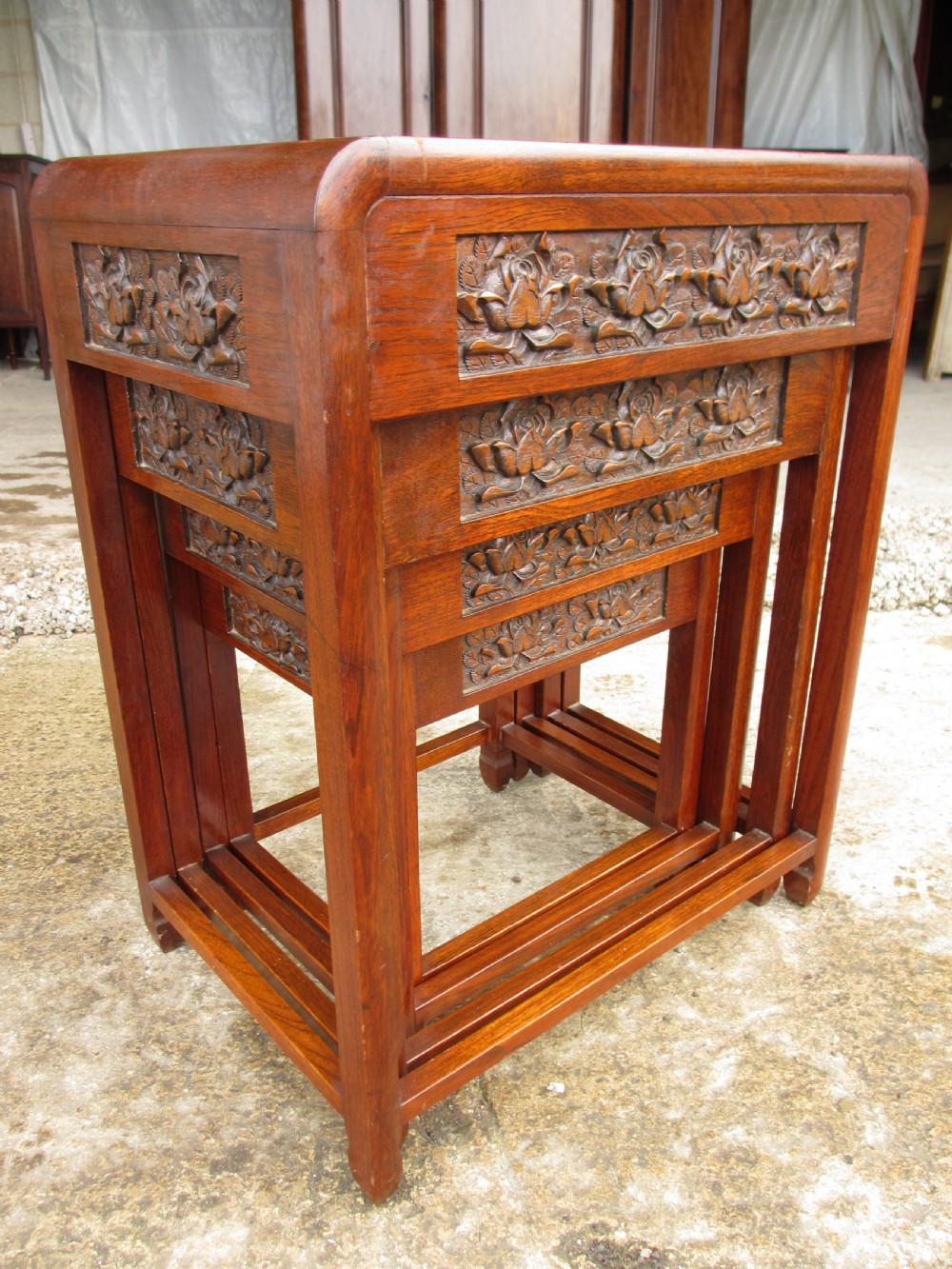 A set of four graduating rosewood side tables nested together, featuring relief-carved lotus friezes and straight legs. View II