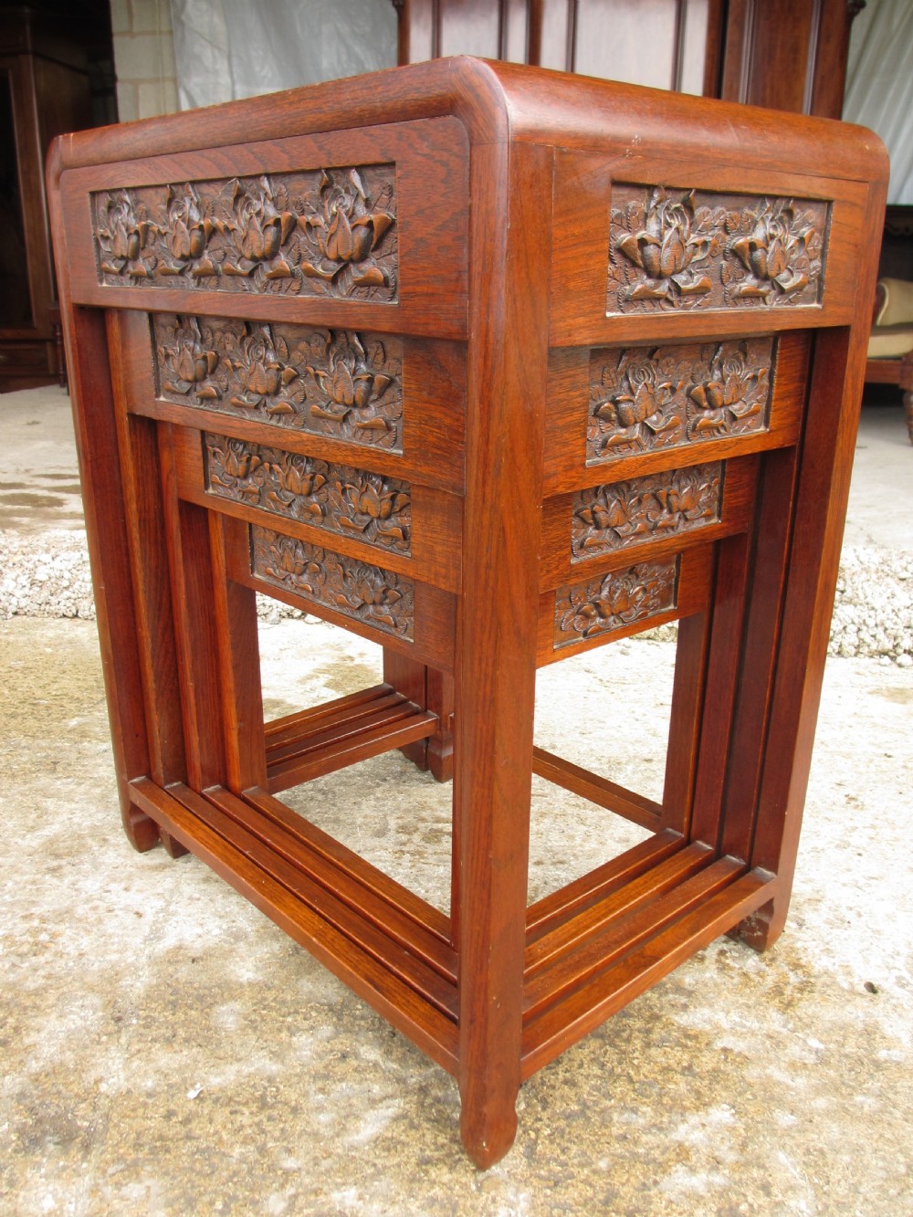 A set of four graduating rosewood side tables nested together, featuring relief-carved lotus friezes and straight legs. View III