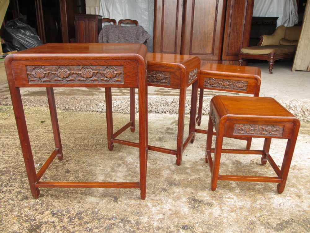 A set of four graduating rosewood side tables nested together, featuring relief-carved lotus friezes and straight legs. View IV