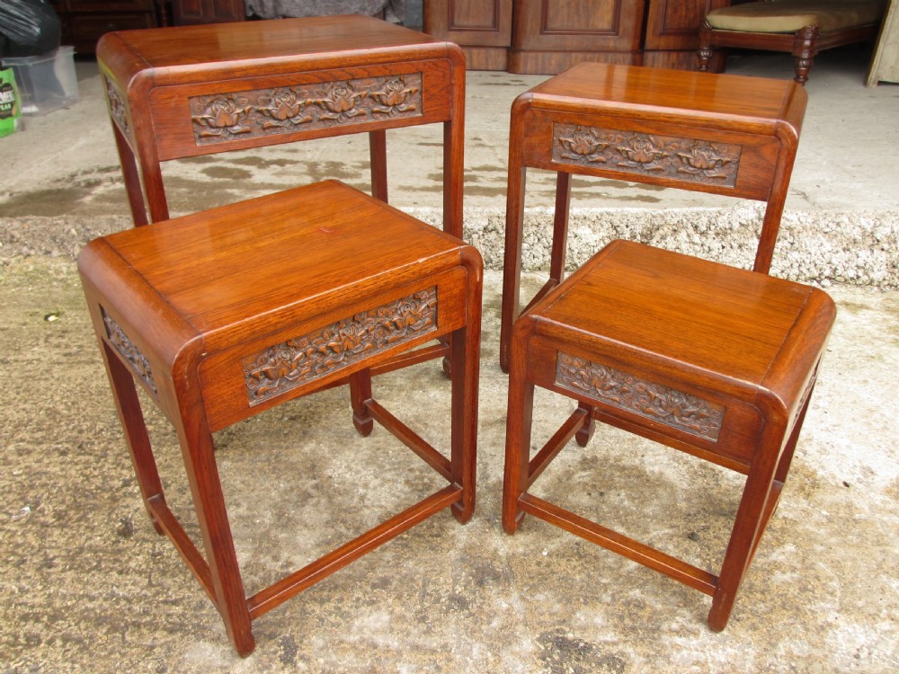 A set of four graduating rosewood side tables nested together, featuring relief-carved lotus friezes and straight legs. View V