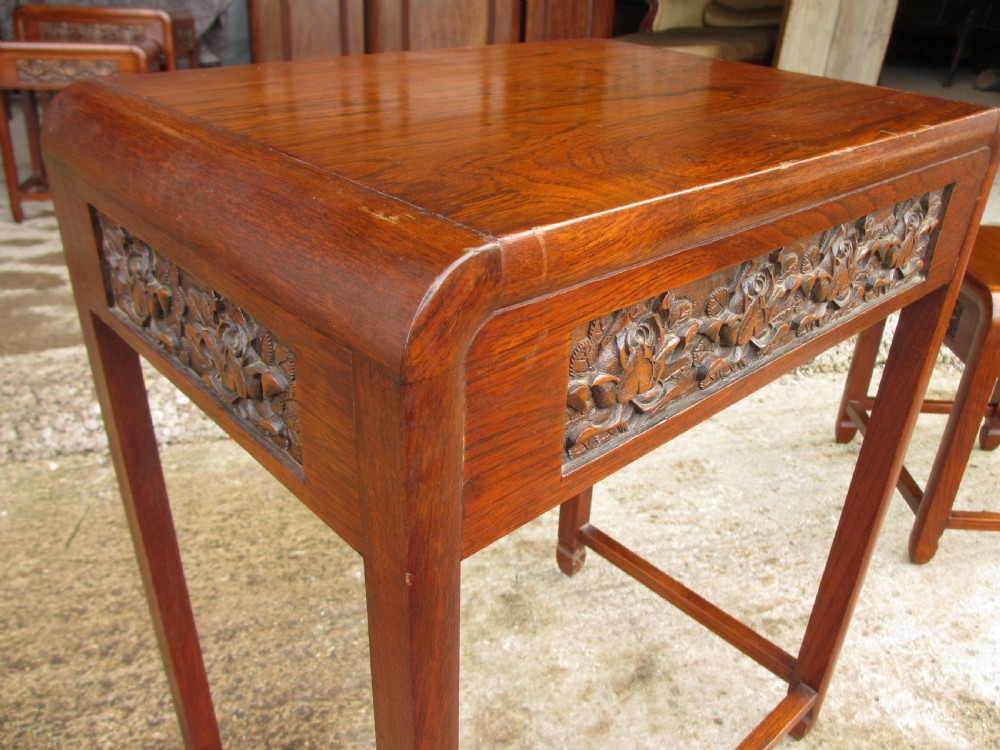 A set of four graduating rosewood side tables nested together, featuring relief-carved lotus friezes and straight legs. View X