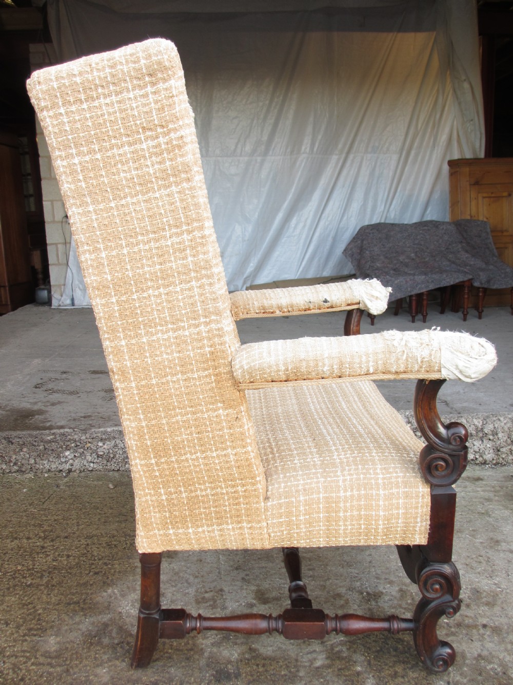 A 19th-century high wingback armchair featuring an intricately carved walnut frame with scroll armrests and neutral woven fabric upholstery. View XIII