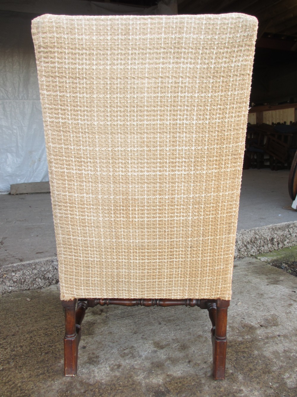 A 19th-century high wingback armchair featuring an intricately carved walnut frame with scroll armrests and neutral woven fabric upholstery. View XIV