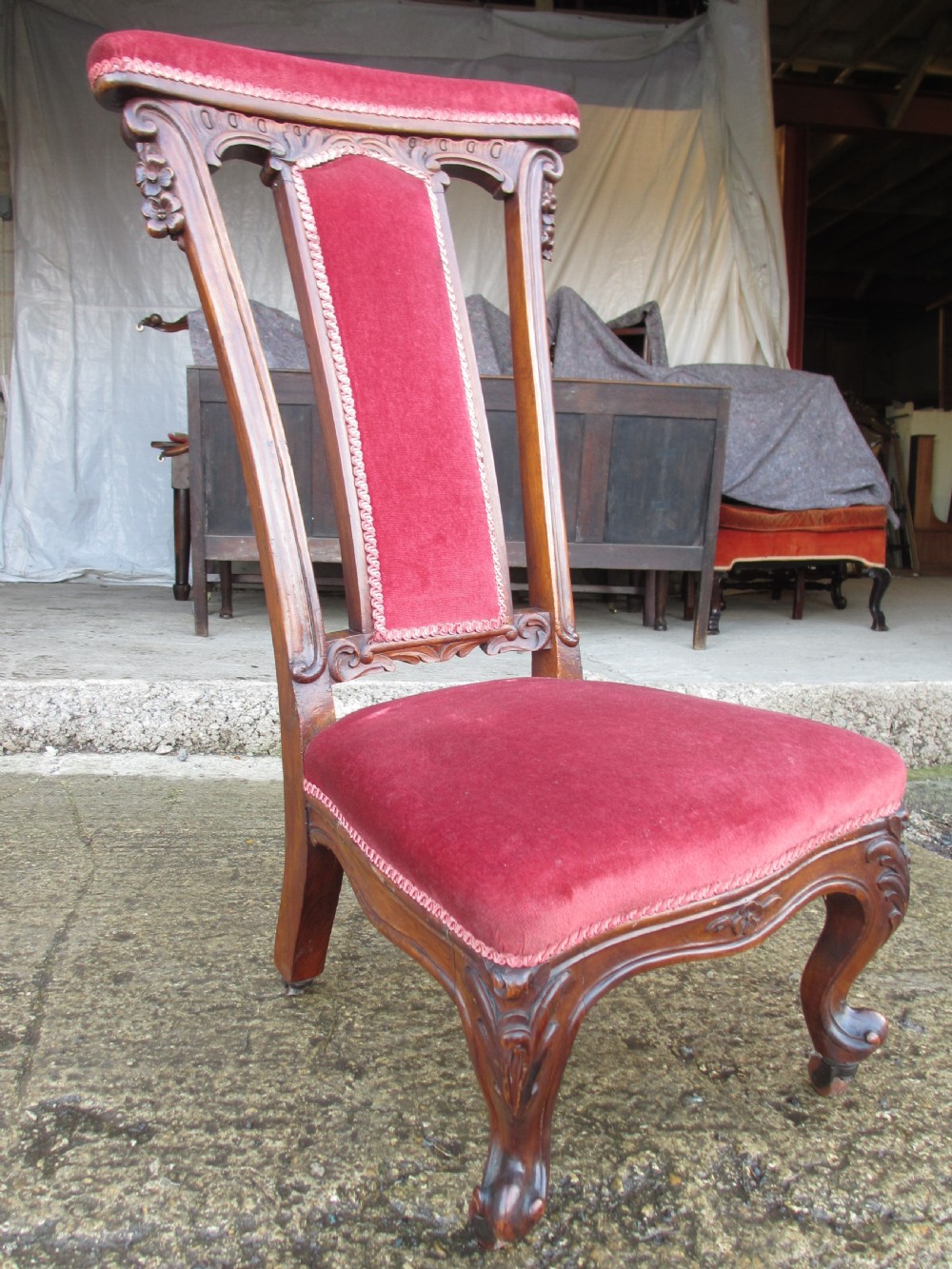 A Victorian carved mahogany prie-dieu chair featuring a tall padded backrest and low seat upholstered in crimson velvet with carved cabriole front legs. View III