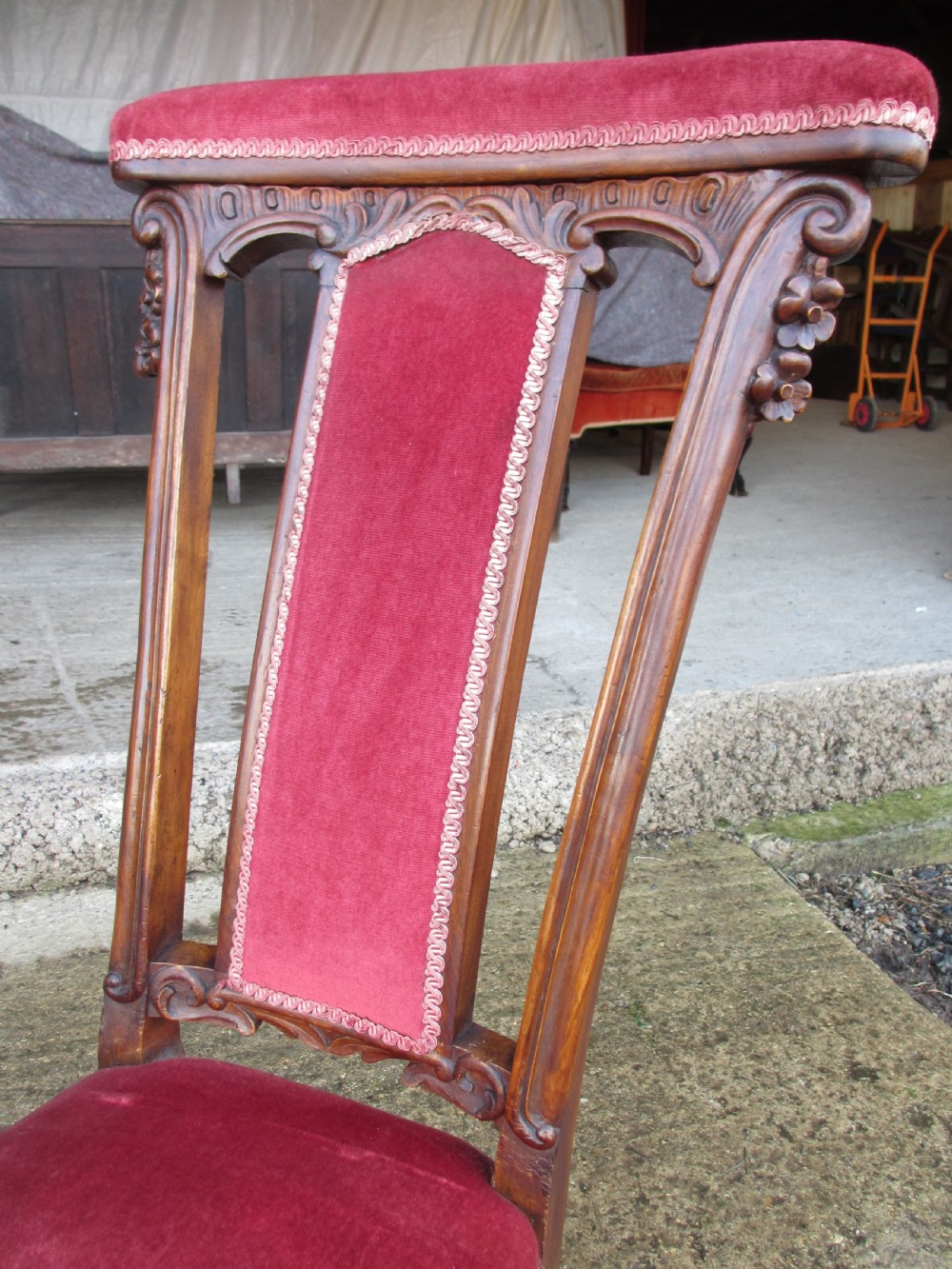 A Victorian carved mahogany prie-dieu chair featuring a tall padded backrest and low seat upholstered in crimson velvet with carved cabriole front legs. View IV