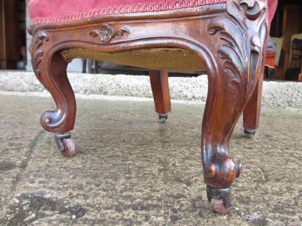 A Victorian carved mahogany prie-dieu chair featuring a tall padded backrest and low seat upholstered in crimson velvet with carved cabriole front legs. View VI