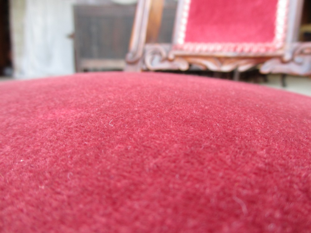 A Victorian carved mahogany prie-dieu chair featuring a tall padded backrest and low seat upholstered in crimson velvet with carved cabriole front legs. View IX