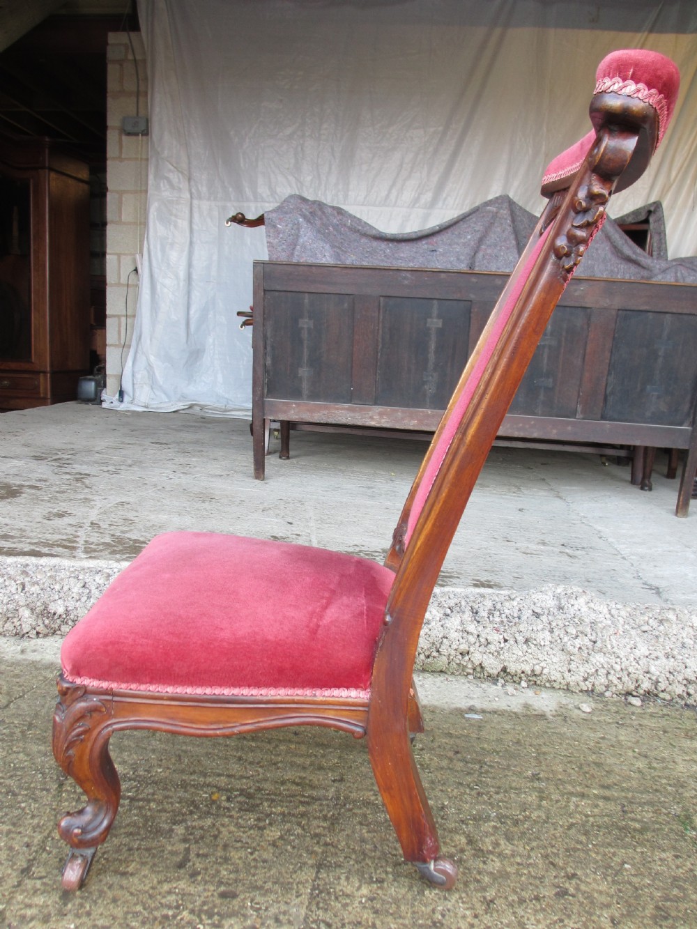 A Victorian carved mahogany prie-dieu chair featuring a tall padded backrest and low seat upholstered in crimson velvet with carved cabriole front legs. View XIII