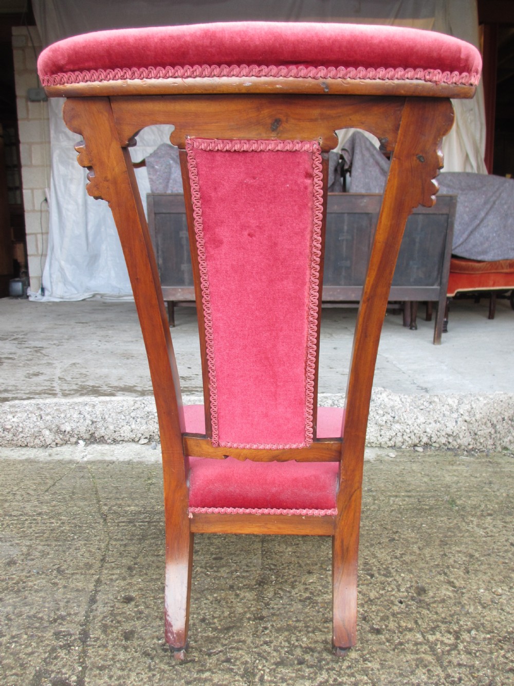 A Victorian carved mahogany prie-dieu chair featuring a tall padded backrest and low seat upholstered in crimson velvet with carved cabriole front legs. View XIV