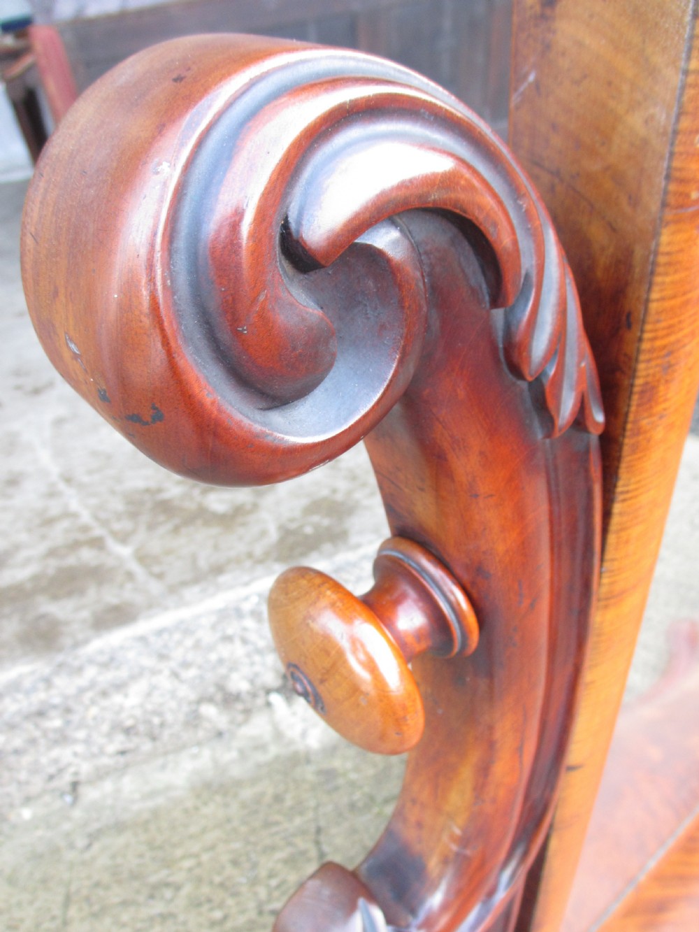 A 19th-century flame mahogany cheval mirror featuring an arched tilting frame suspended between carved scroll supports on a serpentine base. View X