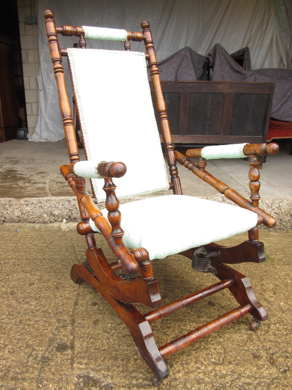 A 19th-century American platform rocking chair crafted from turned beechwood with pale green fabric upholstery on a stationary spring base. View II