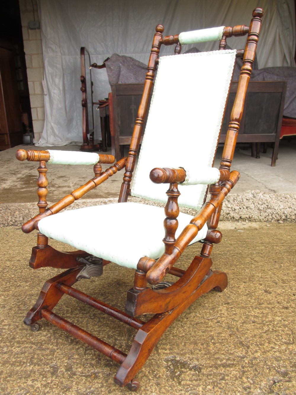 A 19th-century American platform rocking chair crafted from turned beechwood with pale green fabric upholstery on a stationary spring base. View III