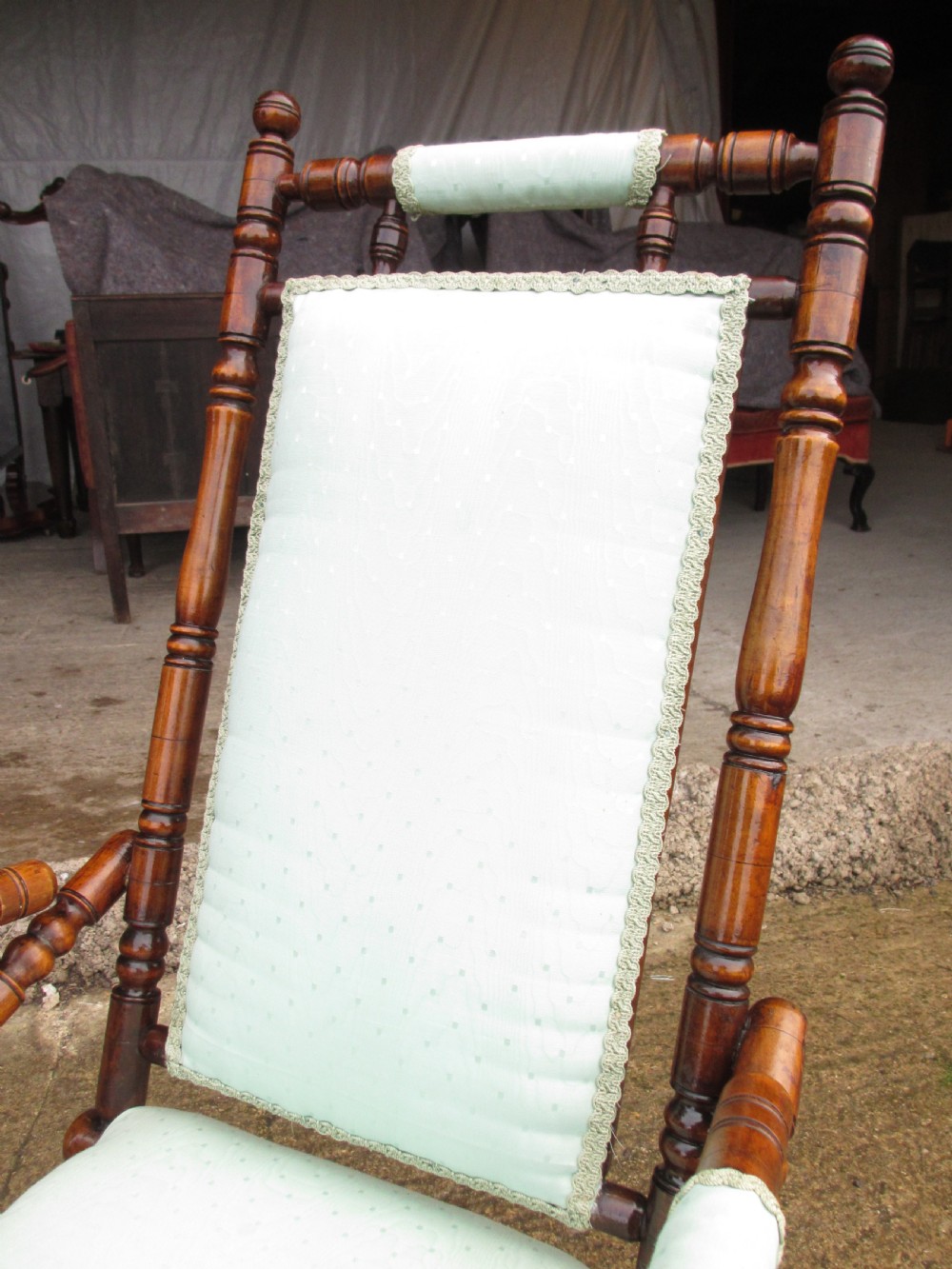 A 19th-century American platform rocking chair crafted from turned beechwood with pale green fabric upholstery on a stationary spring base. View IV