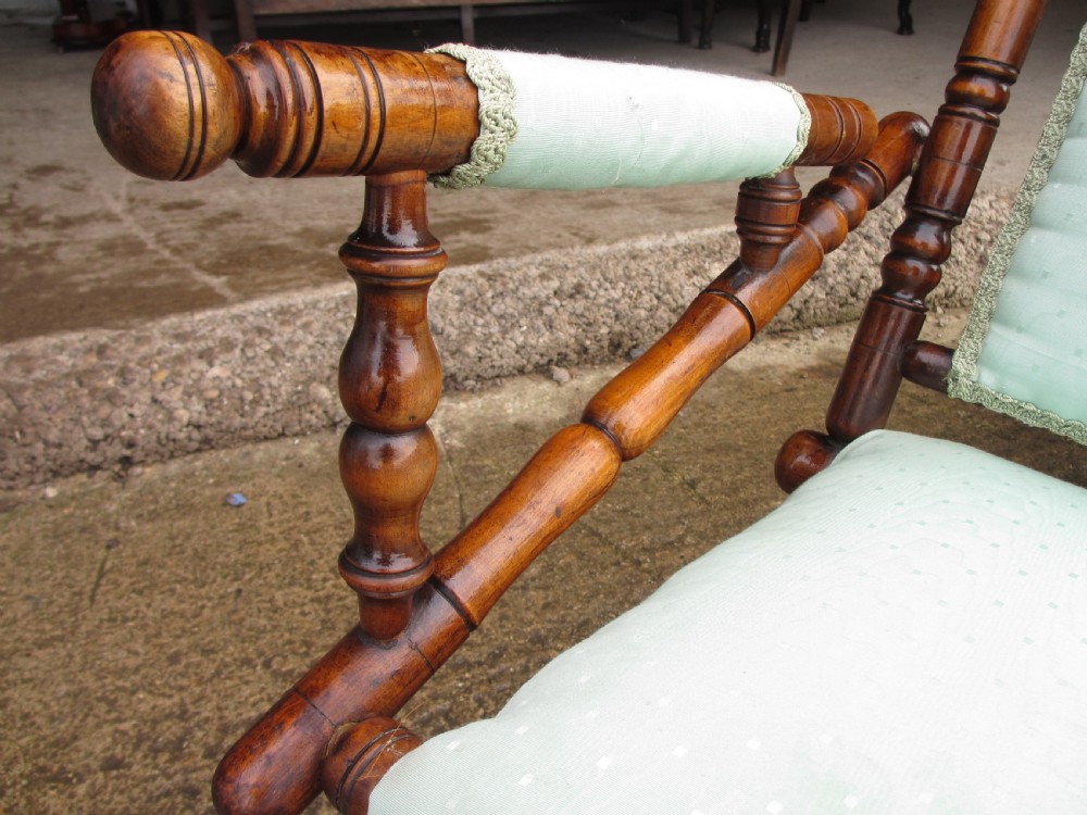A 19th-century American platform rocking chair crafted from turned beechwood with pale green fabric upholstery on a stationary spring base. View X