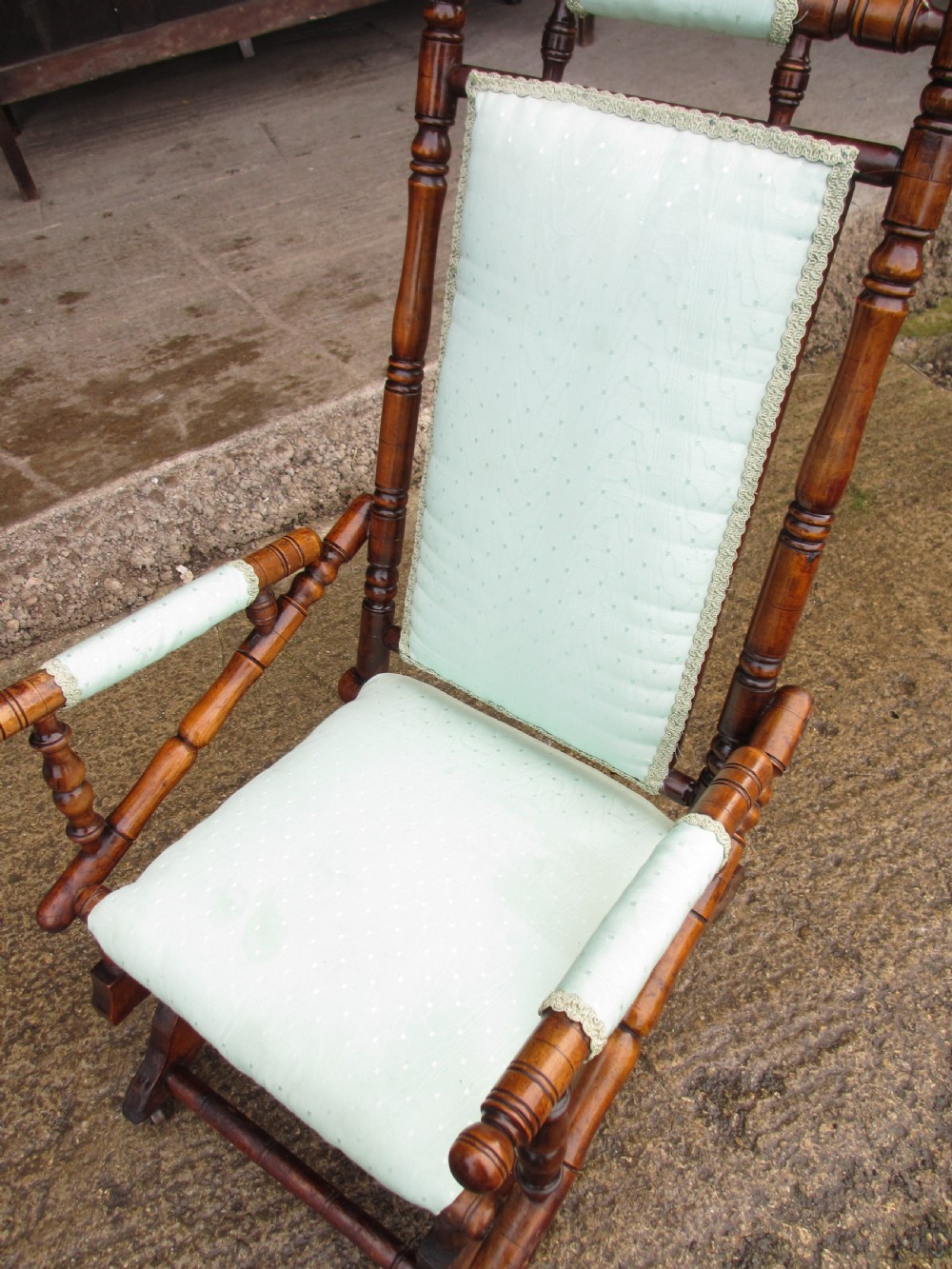 A 19th-century American platform rocking chair crafted from turned beechwood with pale green fabric upholstery on a stationary spring base. View XIII