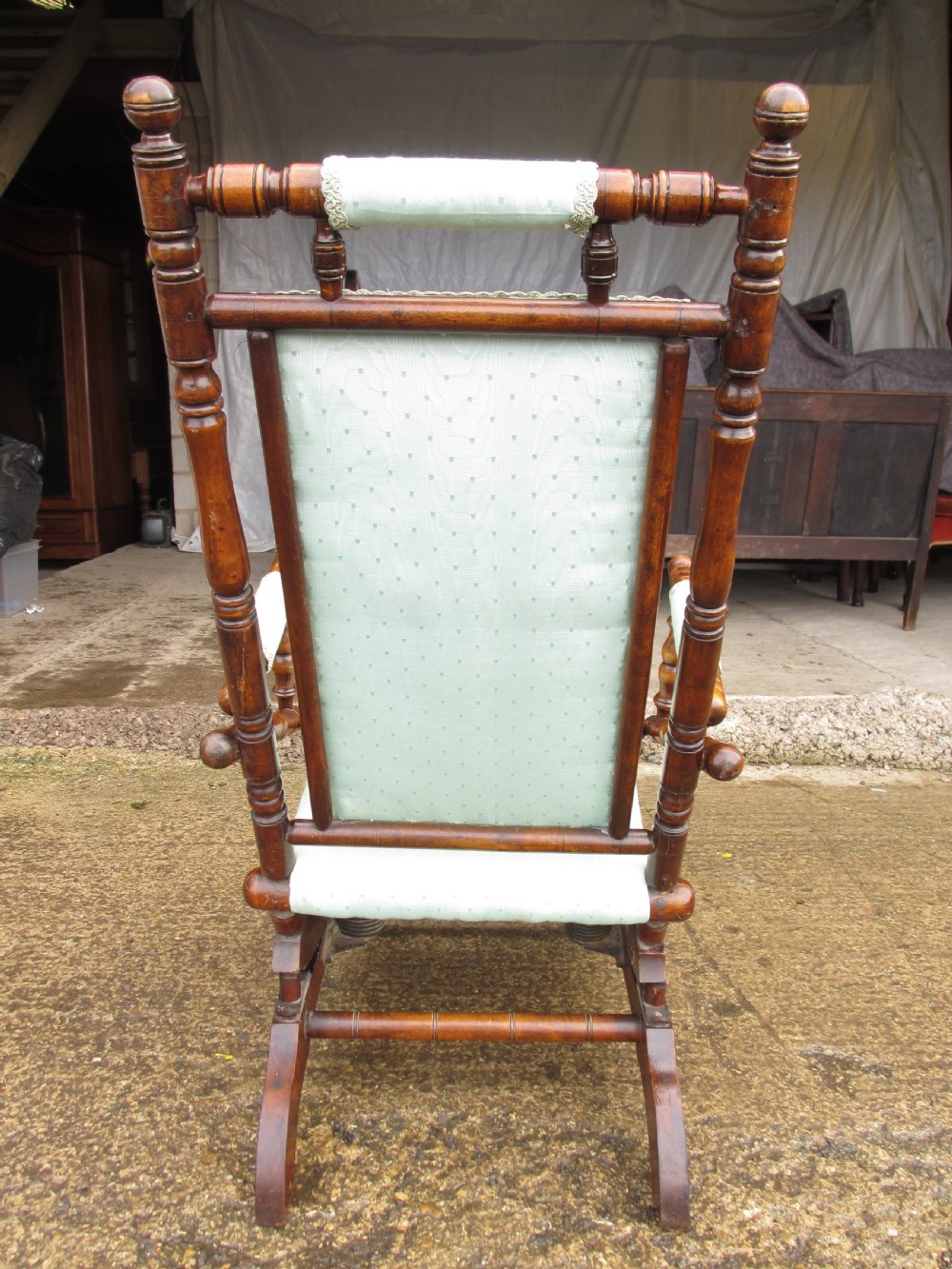 A 19th-century American platform rocking chair crafted from turned beechwood with pale green fabric upholstery on a stationary spring base. View XV