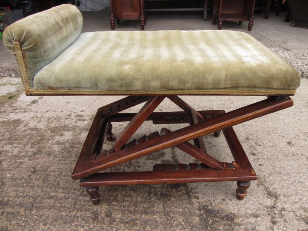 A nineteenth-century beechwood gout stool with an adjustable angled top upholstered in light green striped velvet fabric set upon a dark timber ratchet frame.