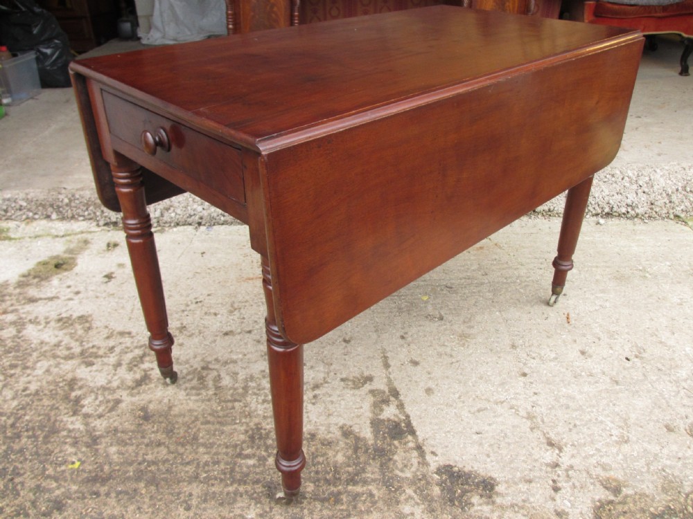 Victorian mahogany Pembroke table with two hinged drop leaves, an end drawer with wooden knobs, and turned legs fitted with brass castors.
