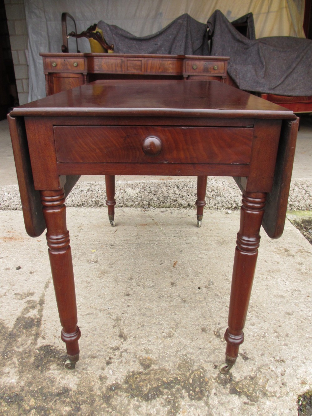 Victorian mahogany Pembroke table with two hinged drop leaves, an end drawer with wooden knobs, and turned legs fitted with brass castors. View II