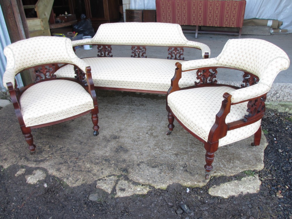 A five-piece antique mahogany parlour suite including a settee, two tub armchairs, and two side chairs with cream patterned upholstery and carved details. View VI