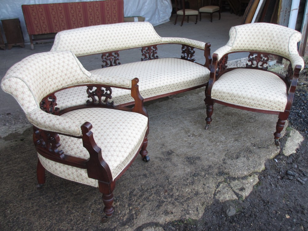 A five-piece antique mahogany parlour suite including a settee, two tub armchairs, and two side chairs with cream patterned upholstery and carved details. View VII