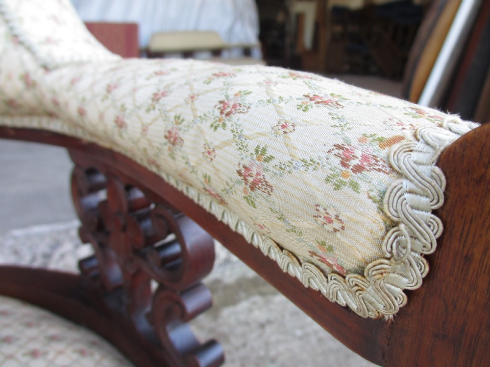 A pair of antique mahogany tub armchairs featuring cream patterned fabric upholstery, openwork carved back splats, and turned front legs on castors. View X