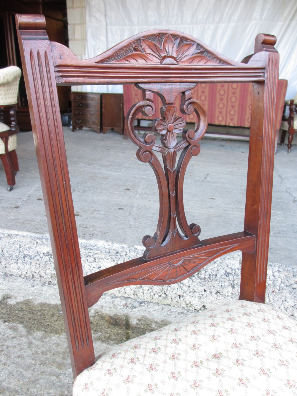 A pair of Edwardian mahogany nursing chairs featuring low seats, pattern-upholstered cushions, carved backs with decorative central splats, and turned front legs with castors. View VI