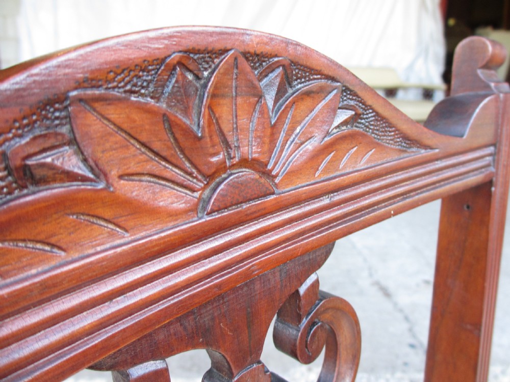 A pair of Edwardian mahogany nursing chairs featuring low seats, pattern-upholstered cushions, carved backs with decorative central splats, and turned front legs with castors. View VII