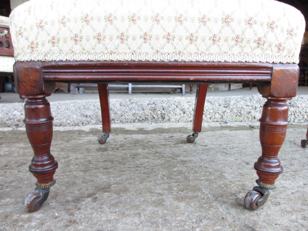 A pair of Edwardian mahogany nursing chairs featuring low seats, pattern-upholstered cushions, carved backs with decorative central splats, and turned front legs with castors. View XI