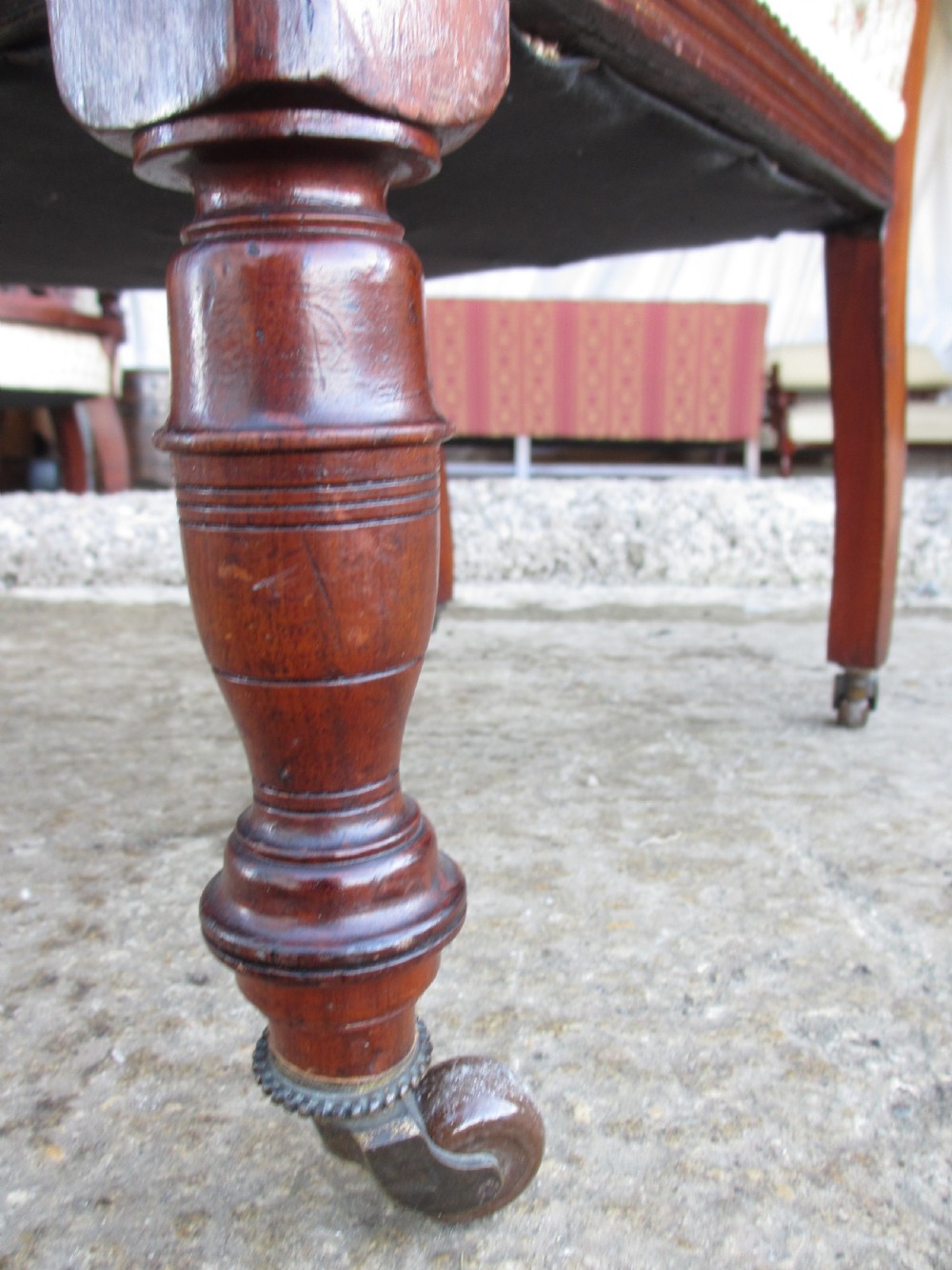 A pair of Edwardian mahogany nursing chairs featuring low seats, pattern-upholstered cushions, carved backs with decorative central splats, and turned front legs with castors. View XII