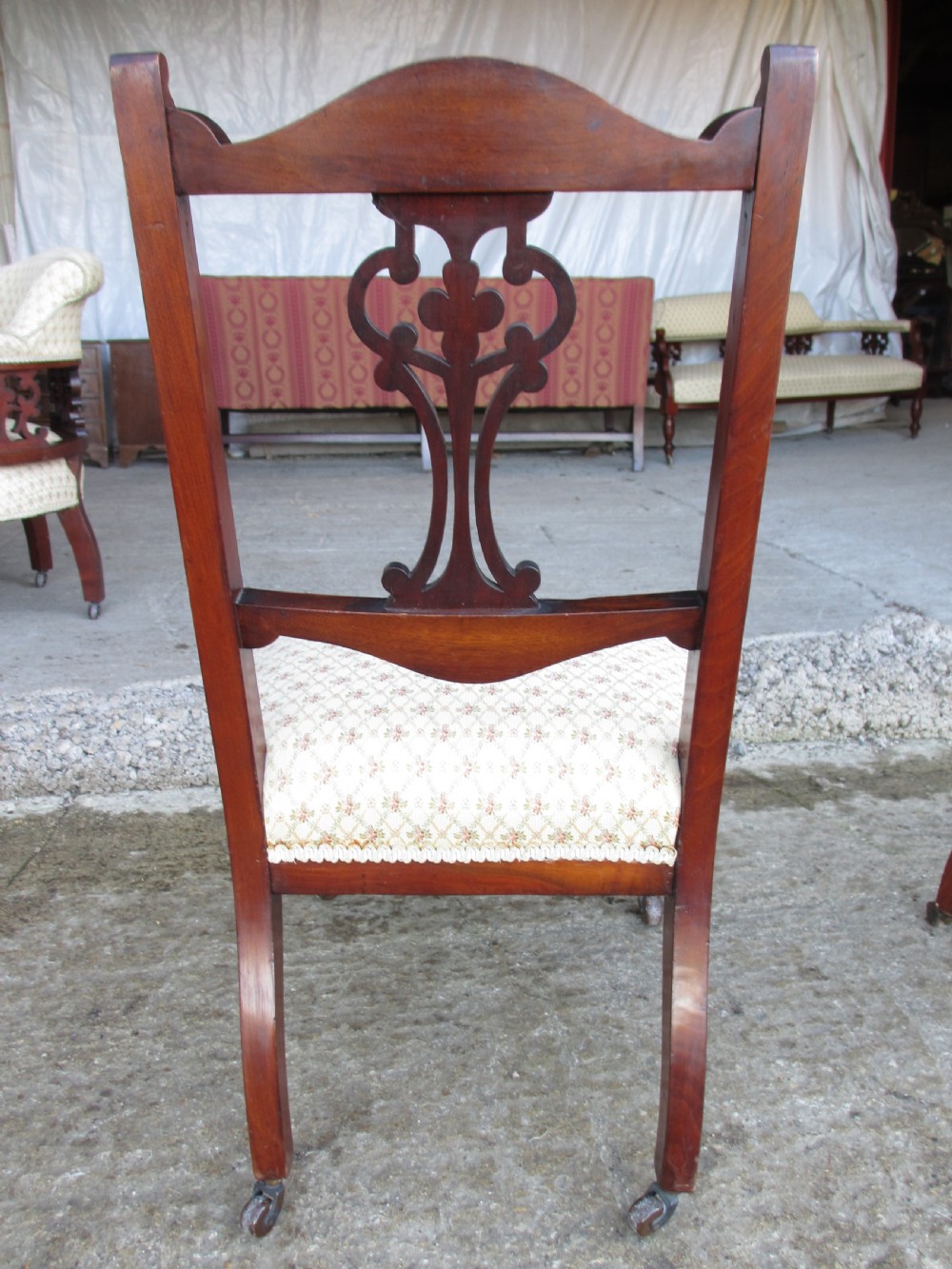 A pair of Edwardian mahogany nursing chairs featuring low seats, pattern-upholstered cushions, carved backs with decorative central splats, and turned front legs with castors. View XIV
