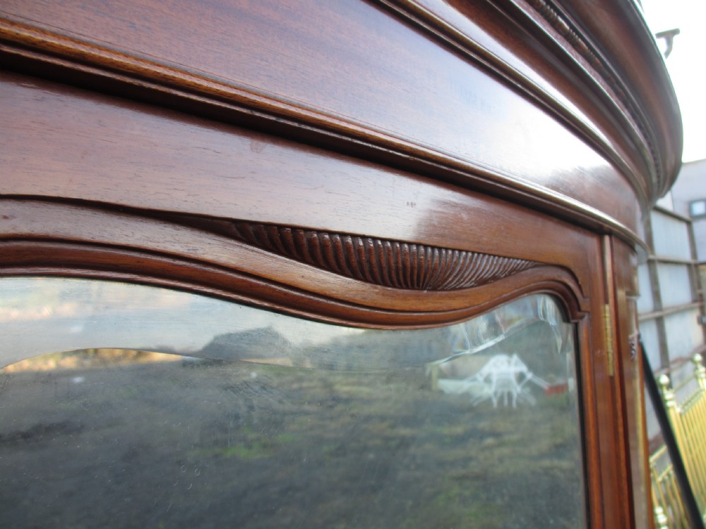 A Victorian bow-fronted mahogany triple wardrobe featuring a central full-length mirror door flanked by panelled flame mahogany doors. View XI
