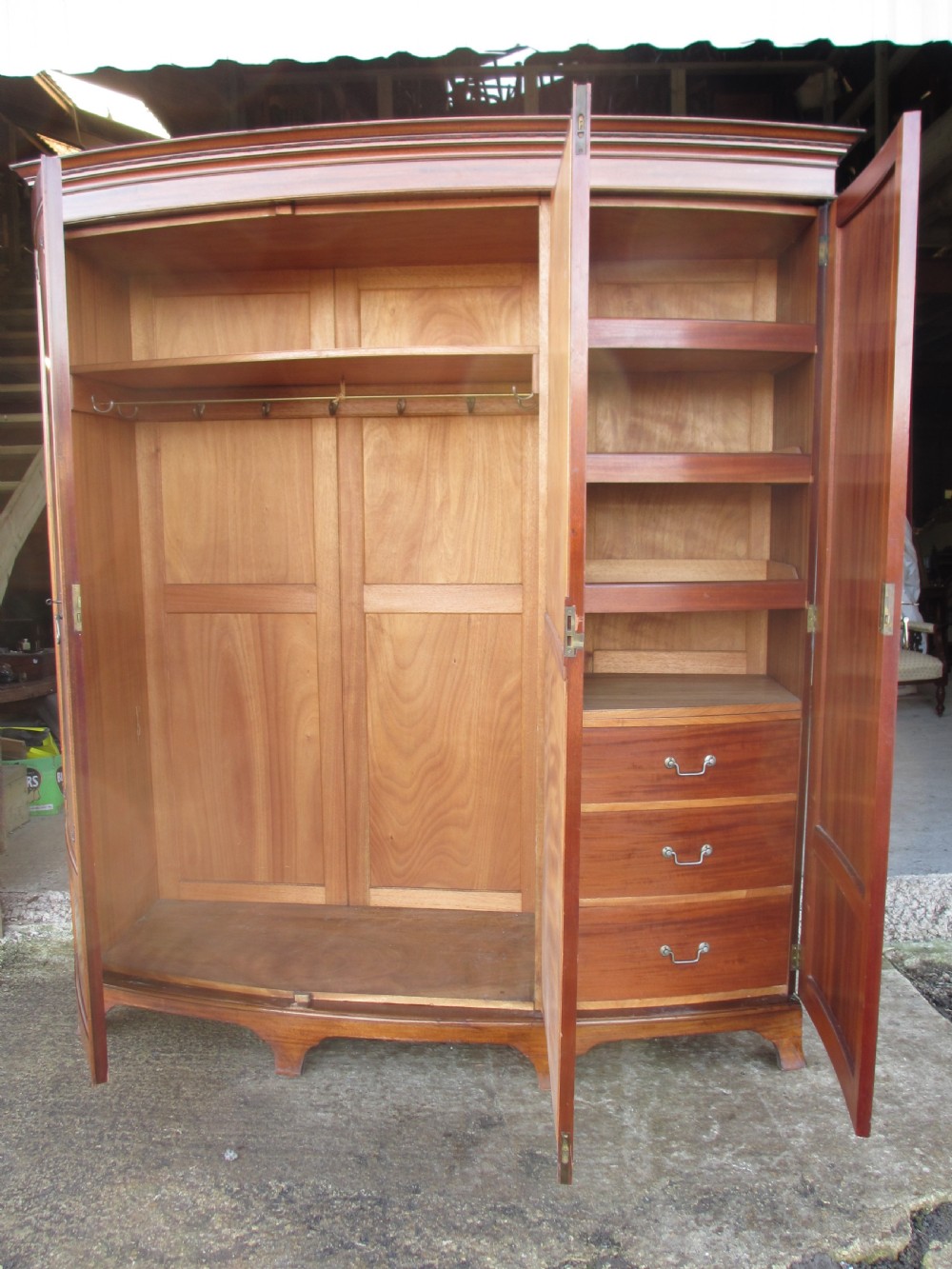 A Victorian bow-fronted mahogany triple wardrobe featuring a central full-length mirror door flanked by panelled flame mahogany doors. View XIV