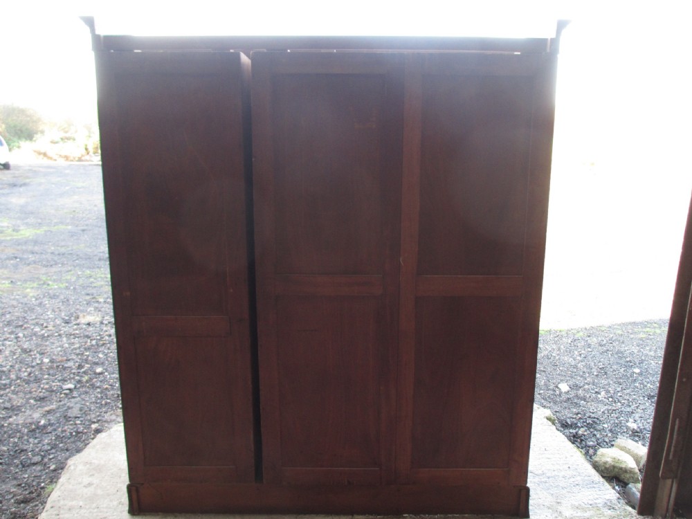 A Victorian bow-fronted mahogany triple wardrobe featuring a central full-length mirror door flanked by panelled flame mahogany doors. View XIX