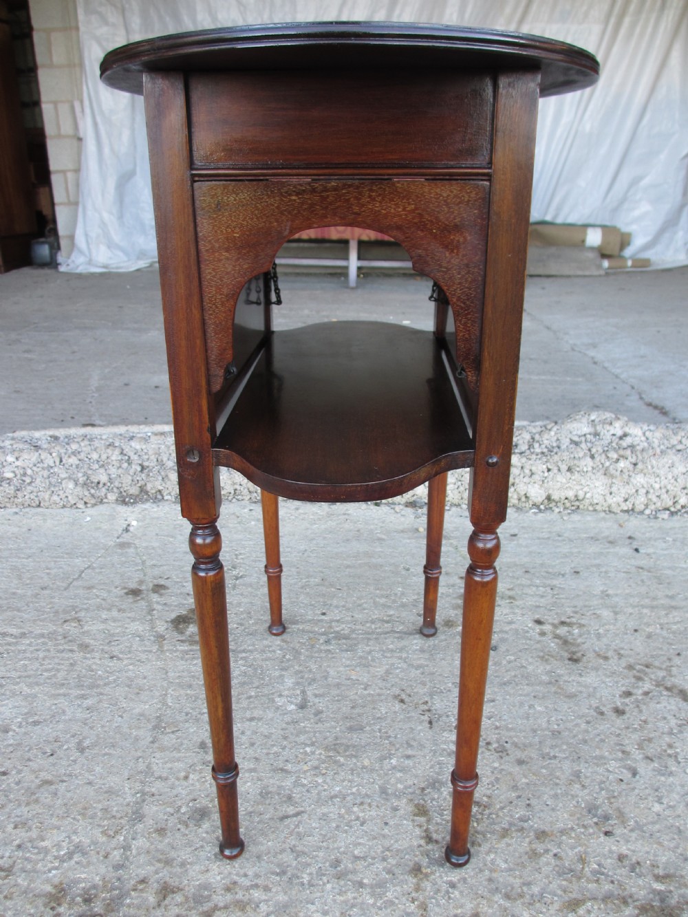 Victorian mahogany oval occasional table with lower shelf and fold-down side leaves held by metal chains. View X