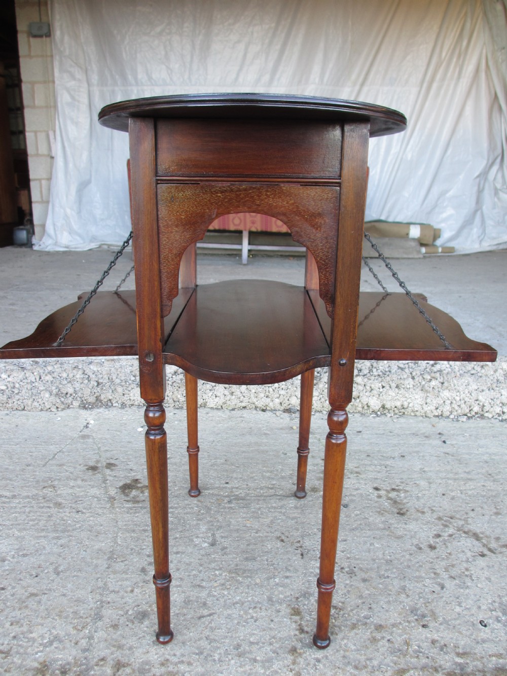 Victorian mahogany oval occasional table with lower shelf and fold-down side leaves held by metal chains. View XI
