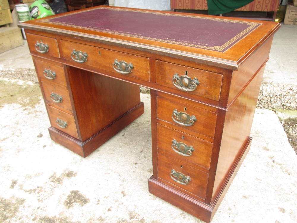 A Victorian walnut pedestal desk featuring nine drawers with brass drop handles and a maroon tooled leather inset writing surface. View III