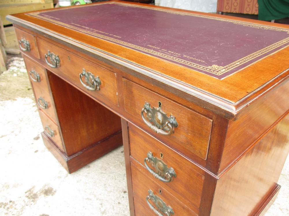 A Victorian walnut pedestal desk featuring nine drawers with brass drop handles and a maroon tooled leather inset writing surface. View IV