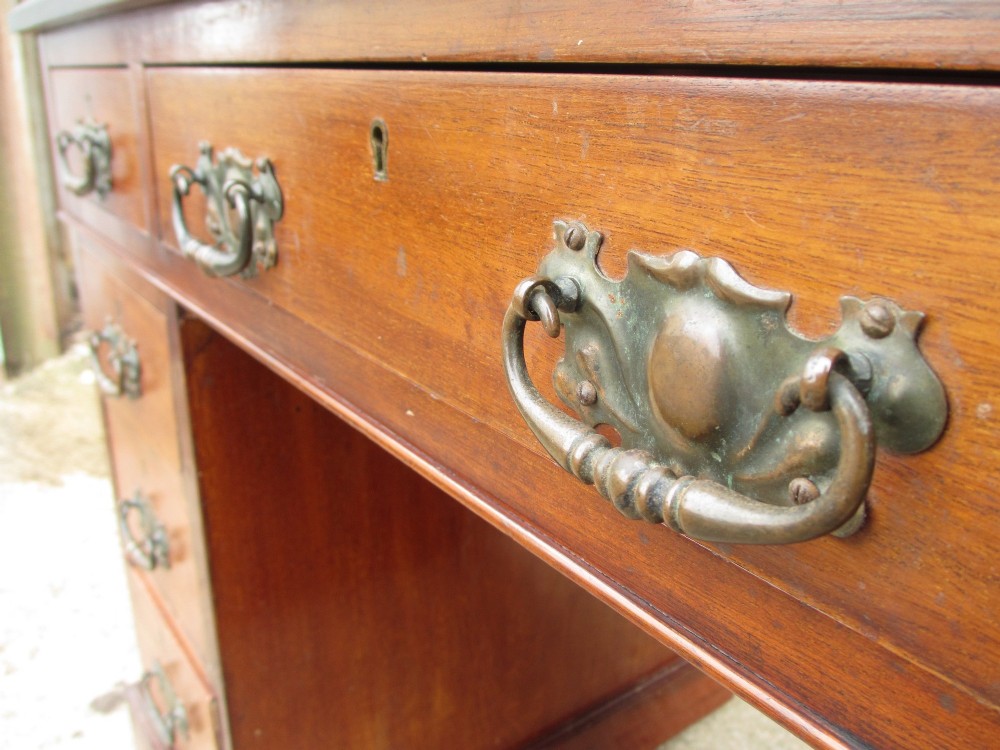 A Victorian walnut pedestal desk featuring nine drawers with brass drop handles and a maroon tooled leather inset writing surface. View V