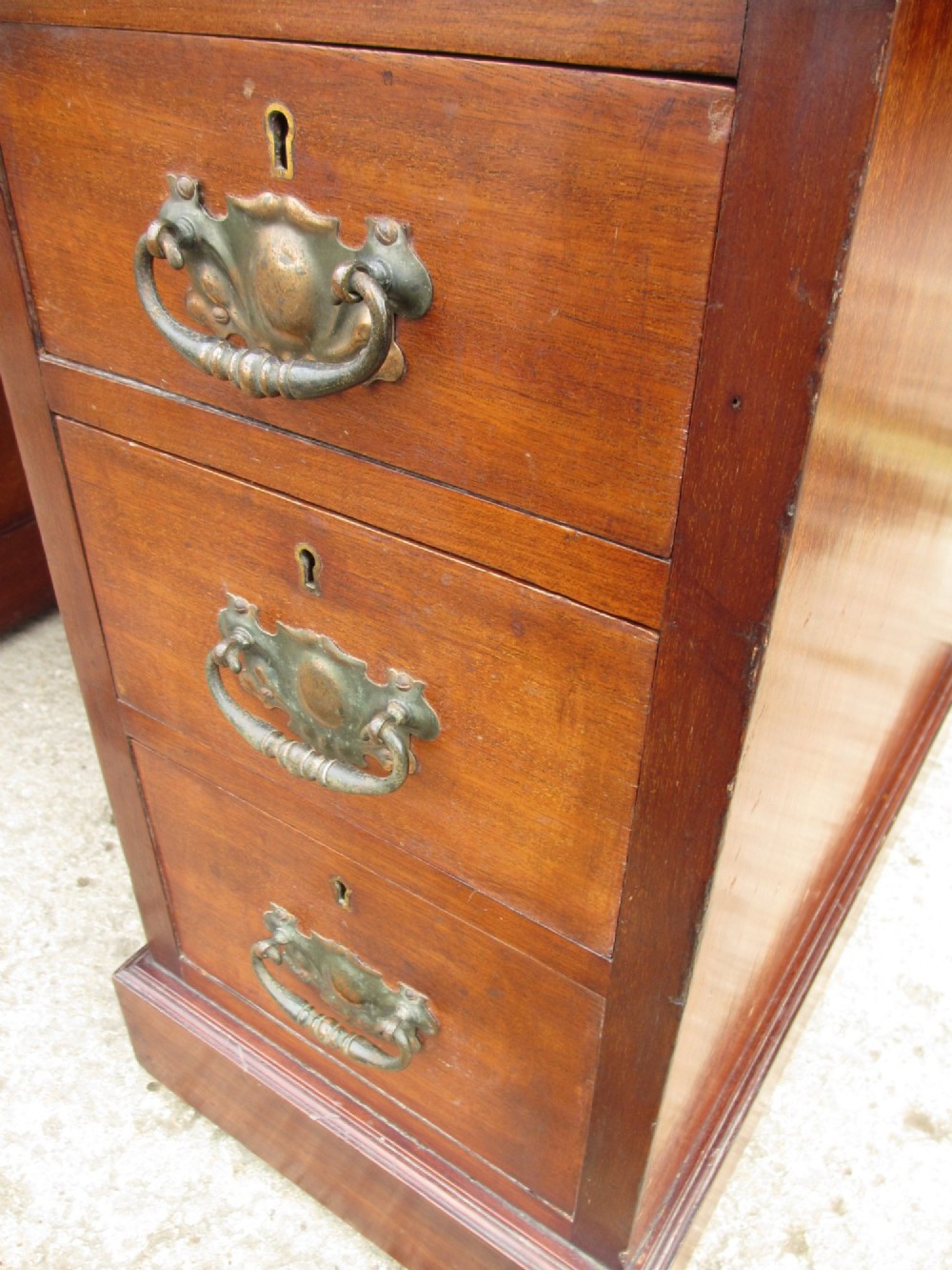 A Victorian walnut pedestal desk featuring nine drawers with brass drop handles and a maroon tooled leather inset writing surface. View VI