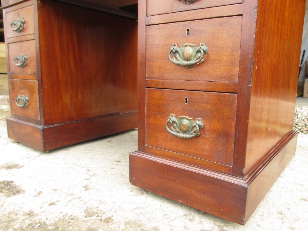 A Victorian walnut pedestal desk featuring nine drawers with brass drop handles and a maroon tooled leather inset writing surface. View VII